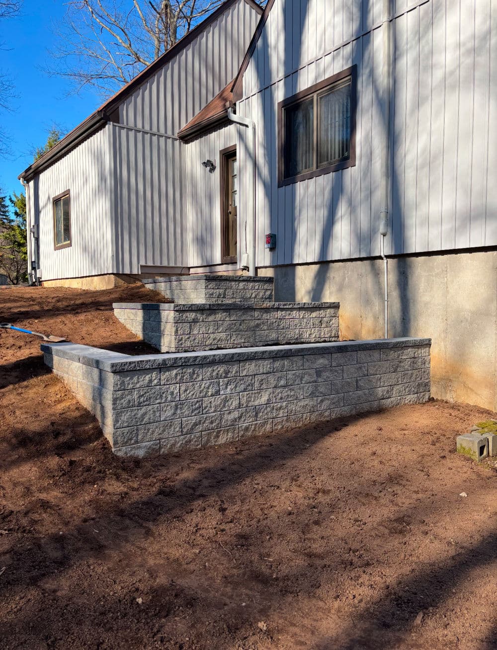 Landscape design featuring stone steps leading to a modern home exterior.
