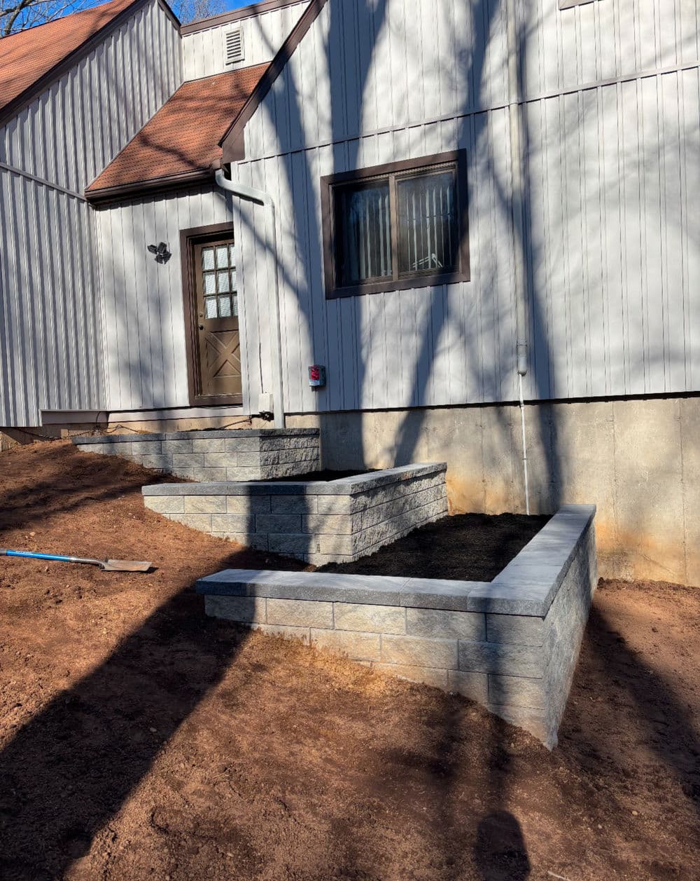 Stone retaining wall and pathway leading to a stylish home entrance on a sunny day.