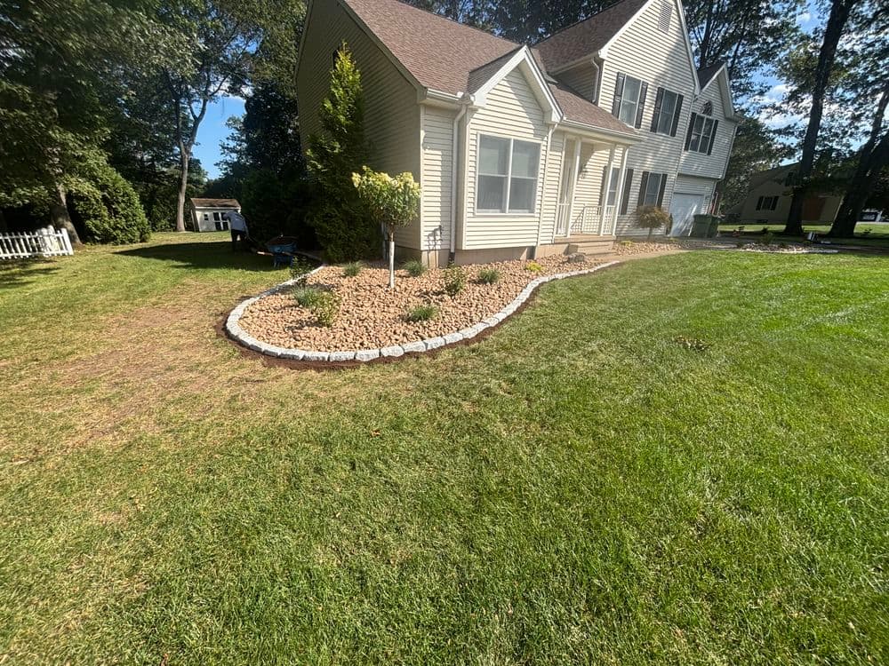 Landscaped yard with a Belgium block border and well-maintained grass near a house.